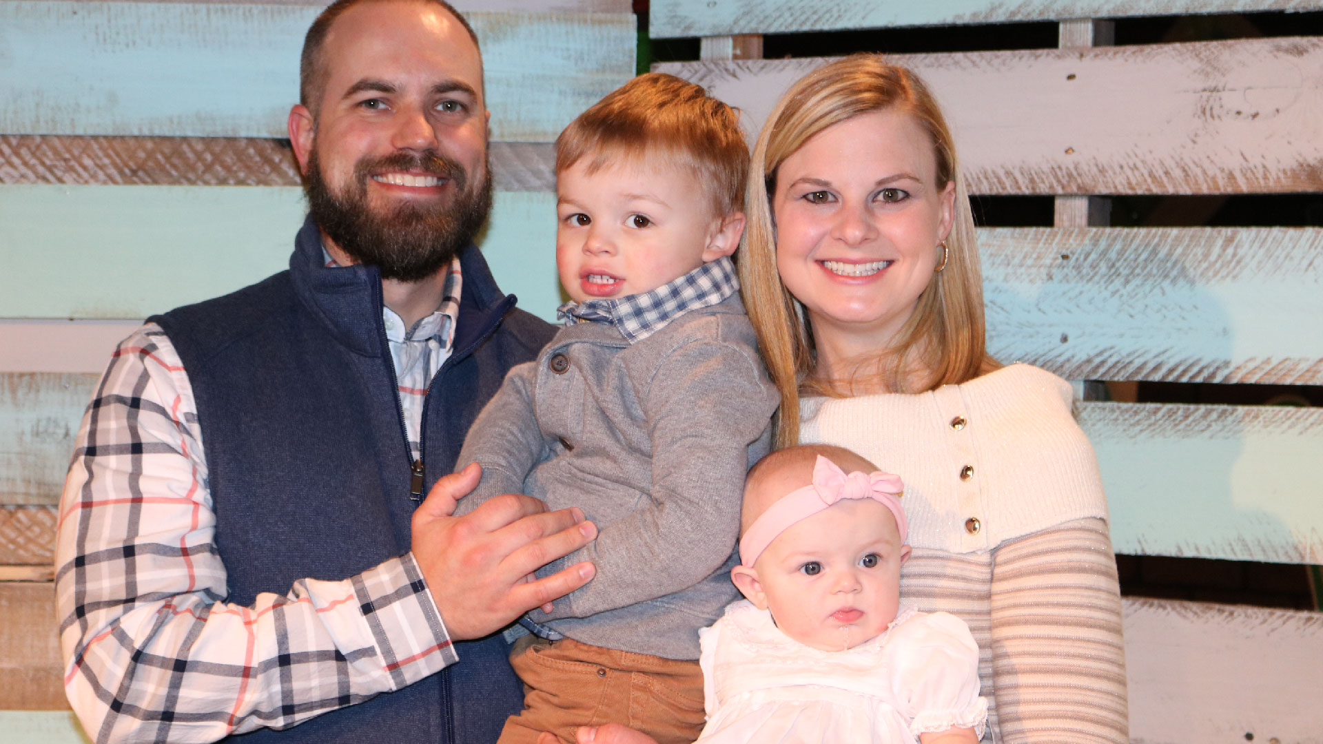 A family with two small children smiling for Brookwood Church parent dedication